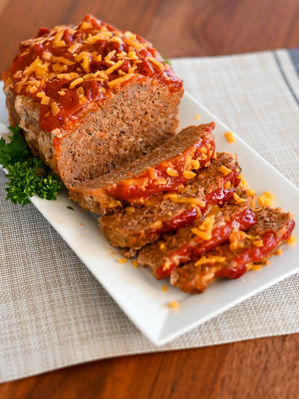 Sliced meatloaf without onions on a white platter. 