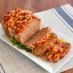 Sliced meatloaf without onions on a white platter.