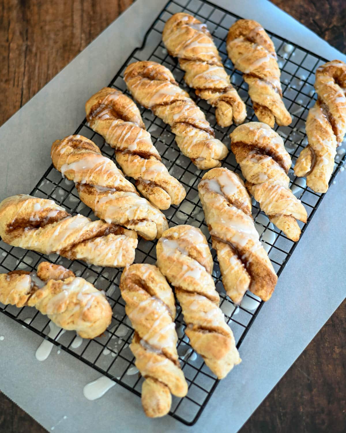 Cinnamon twists with glaze on a black rack. 