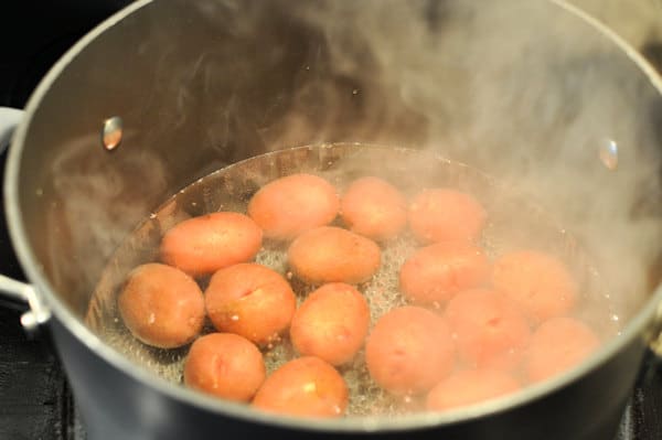 a pot of boiling water cooking red potatoes