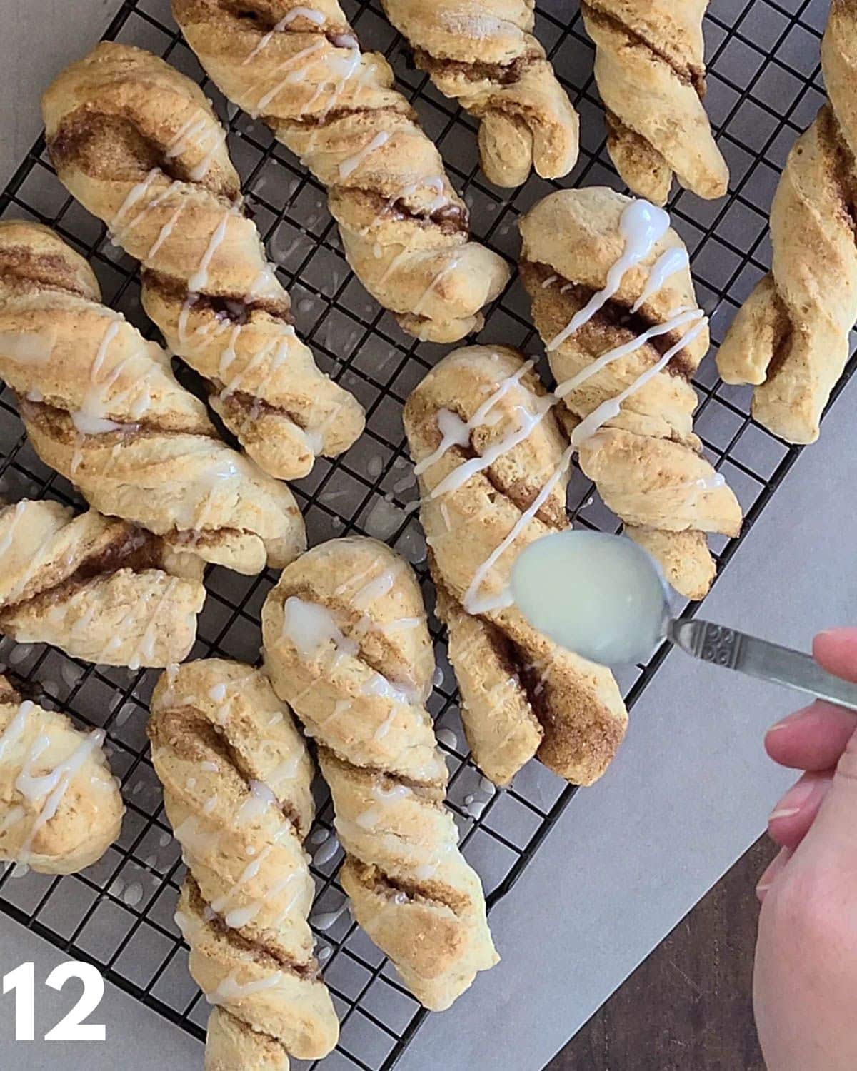 Glaze being drizzled over cinnamon twists. 