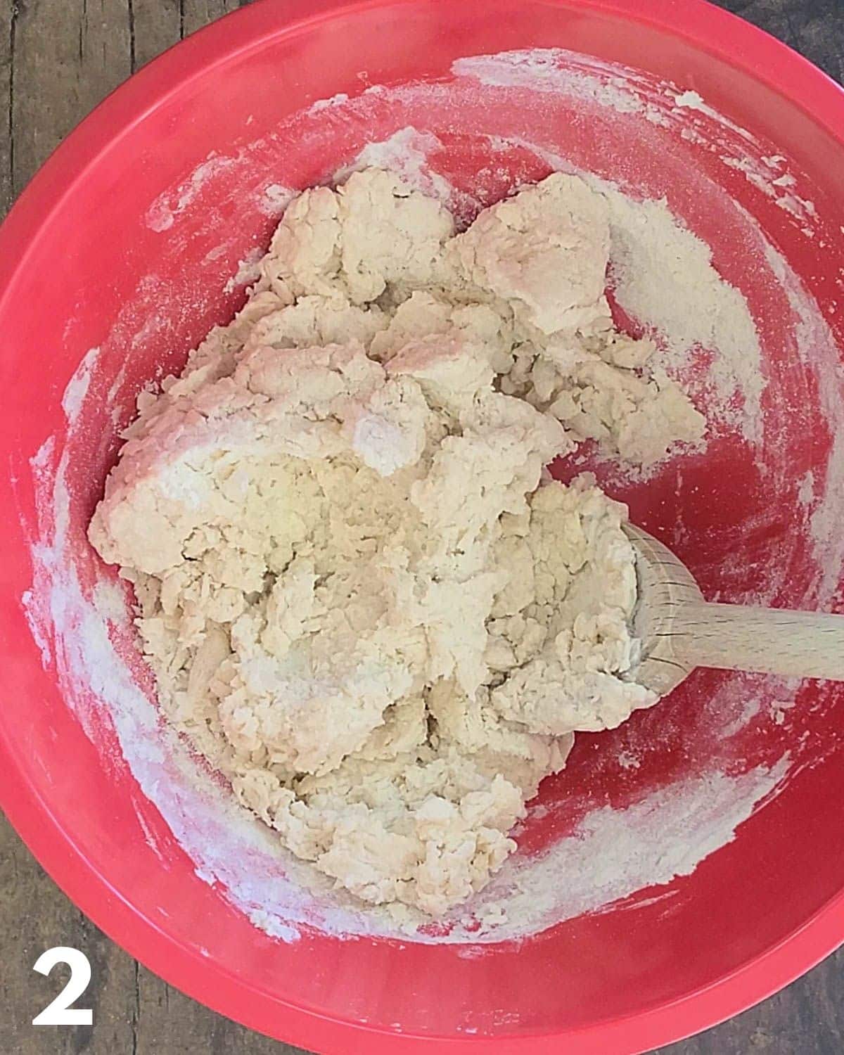 Dough being mixed in a large red bowl. 