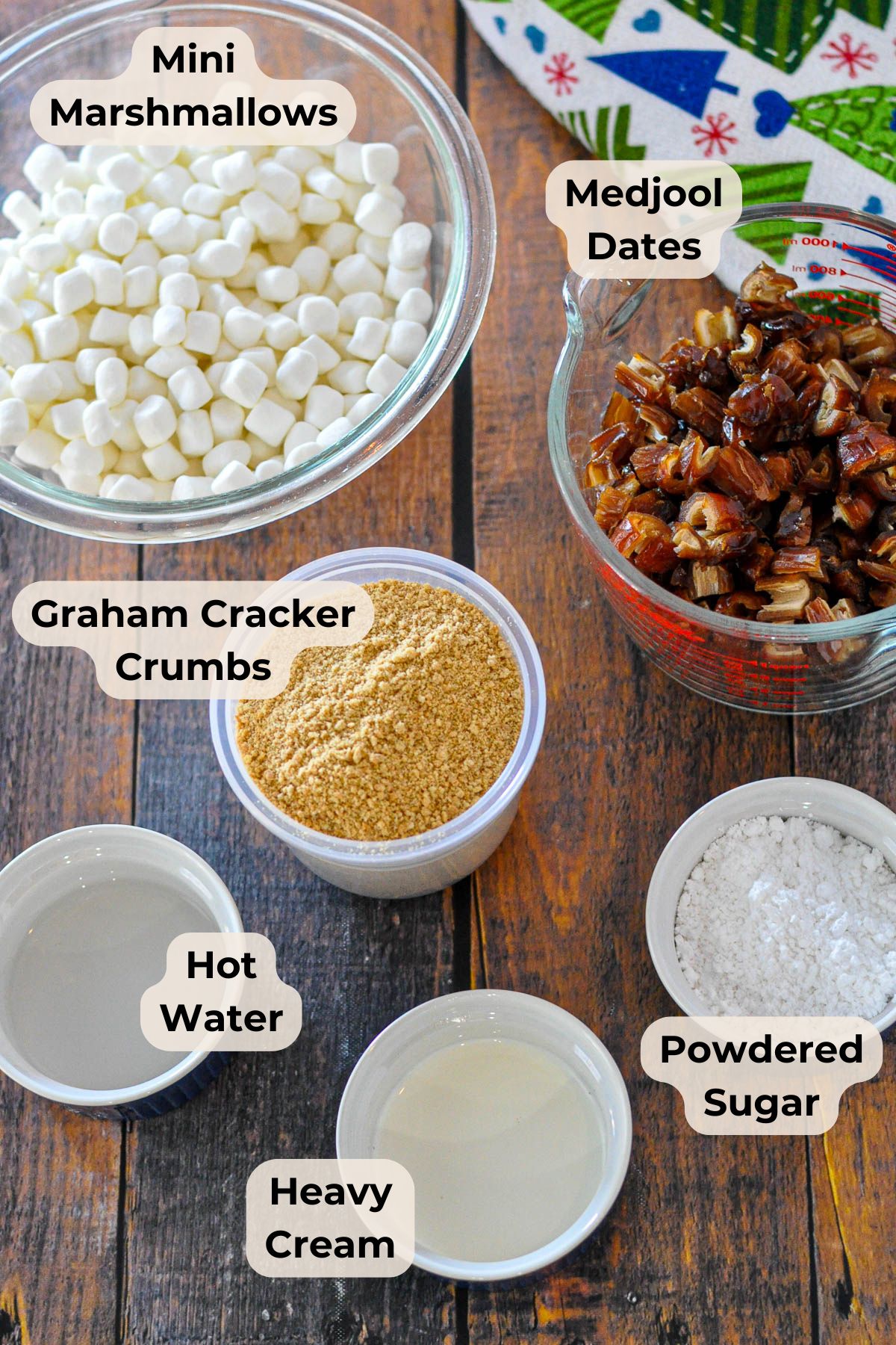 Holiday Date Roll Bowls of mini marshmallows, chopped medjool dates, graham cracker crumbs, hot water, heavy cream, and powdered sugar-perfect for making an old fashioned date roll or a festive Holiday Date Roll dessert.