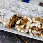 Sliced Holiday Date Roll or old fashioned date roll with powdered sugar and marshmallows on a white plate.