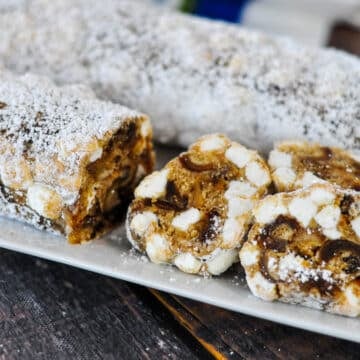 Sliced Holiday Date Roll or old fashioned date roll with powdered sugar and marshmallows on a white plate.