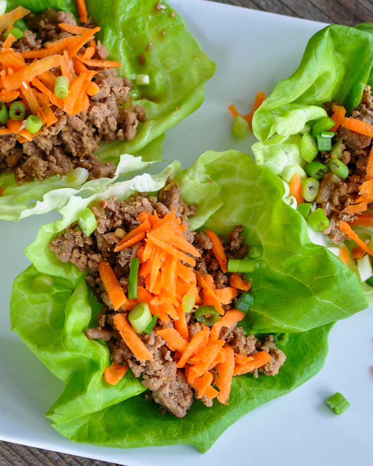 ginger and garlic spiced ground meat in a lettuce cup topped with carrots