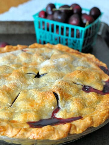 a just baked cherry pie sitting in a baking sheet.