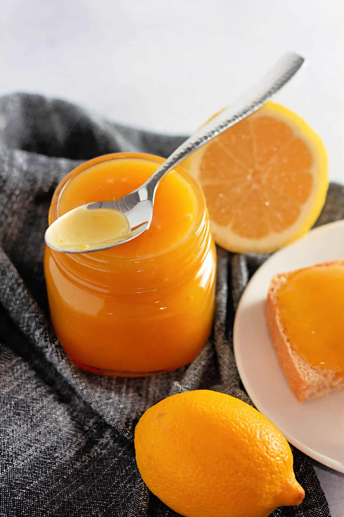 A jar of homemade lemon curd next to a plate with toast.