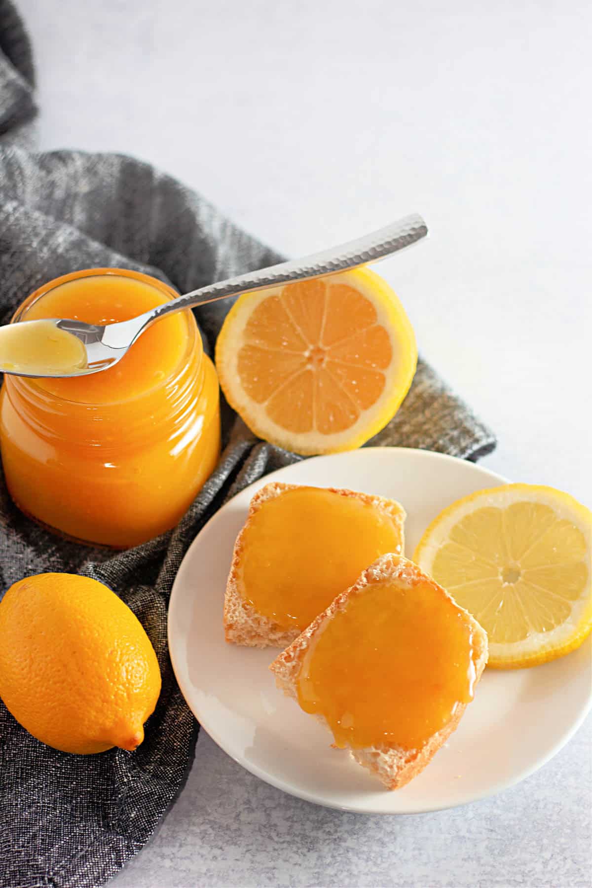 A jar of homemade lemon curd next to a plate with toast.