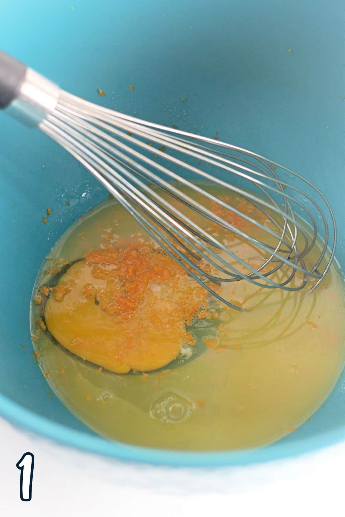 Egg, orange juice, and sugar in a mixing bowl with a whisk. 