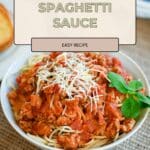 Bowl of spaghetti with Ground Turkey Spaghetti Sauce, topped with grated cheese and basil, on a table.