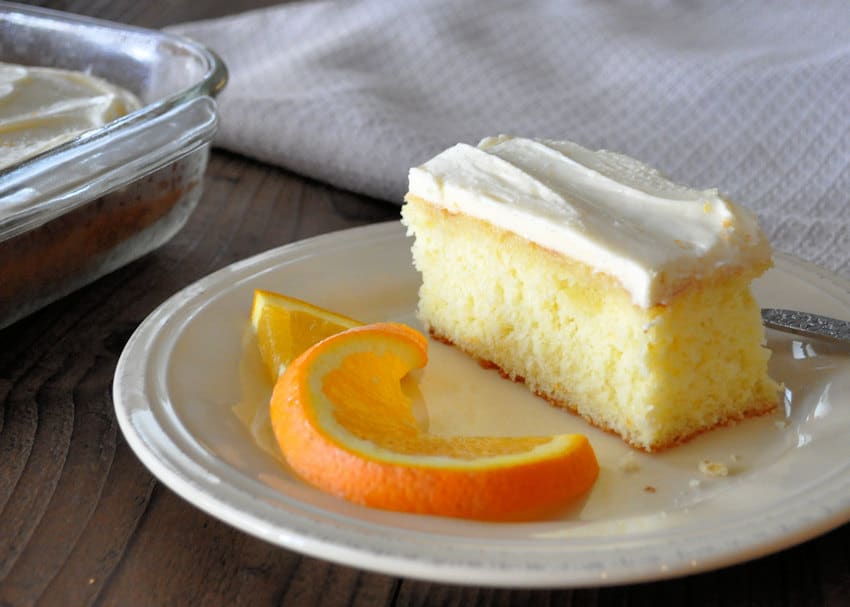 frosted cake with an orange slice on a beige plate
