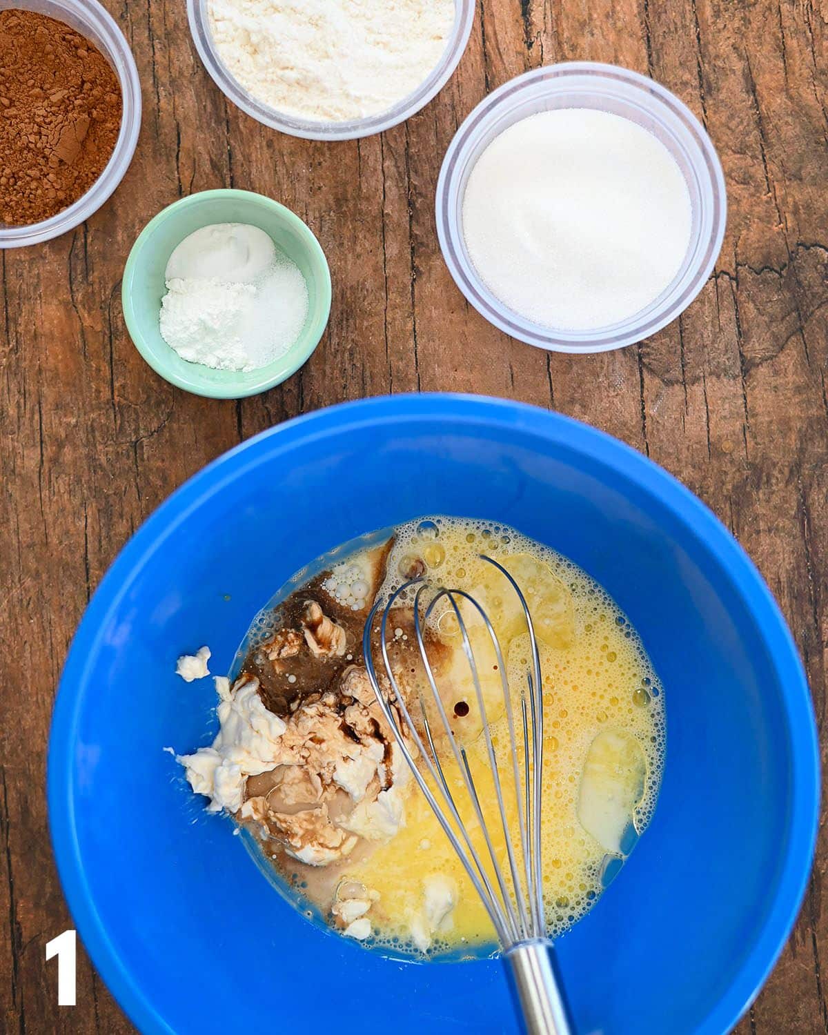 Egg, milk, mayonnaise, and vanilla in a blue mixing bowl. 