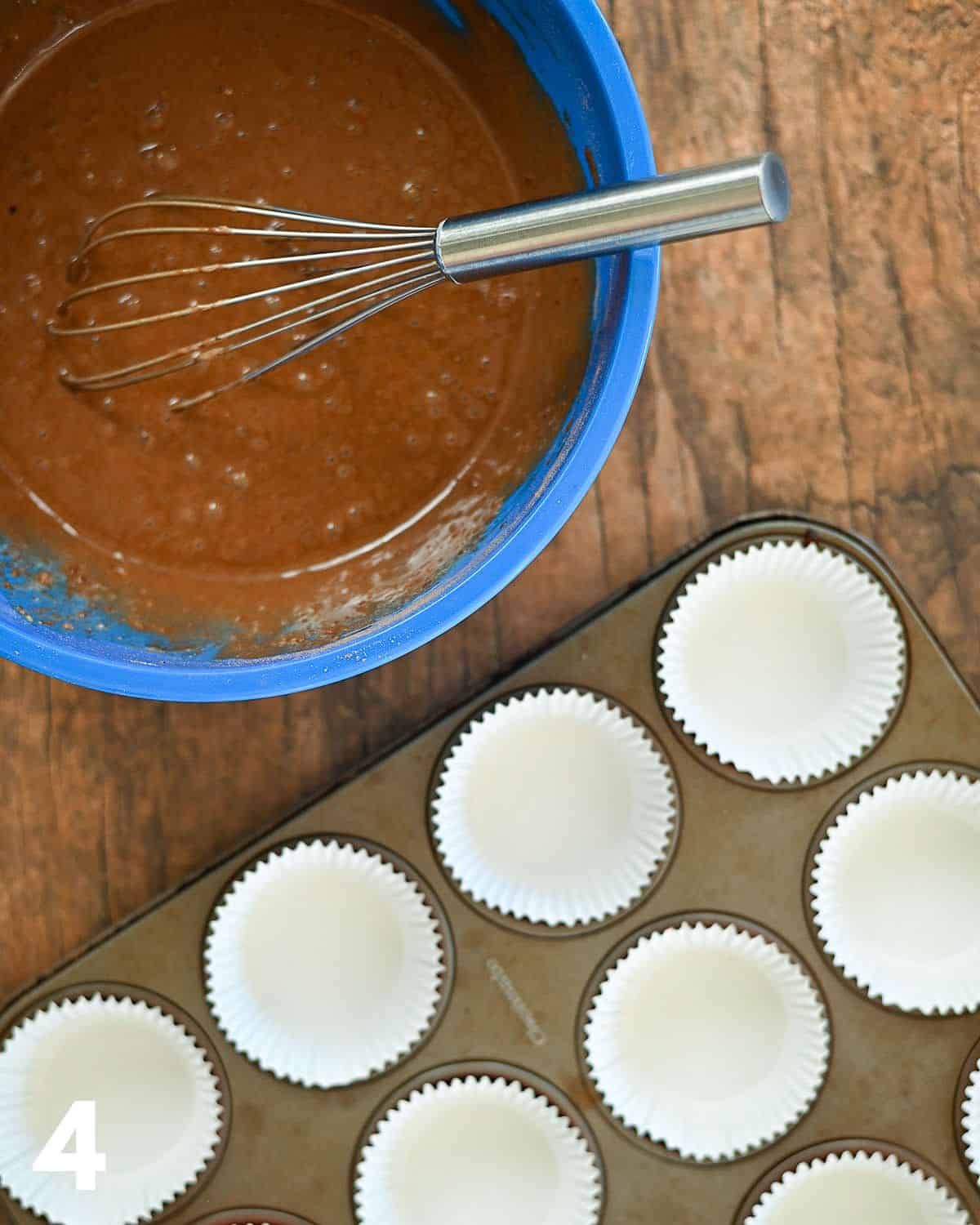 Chocolate pancake batter in a bowl next to a muffin tin.