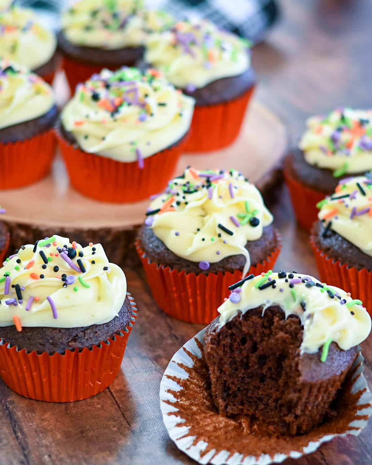 Chocolate cupcakes with butter frosting topped with colorful sprinkles.