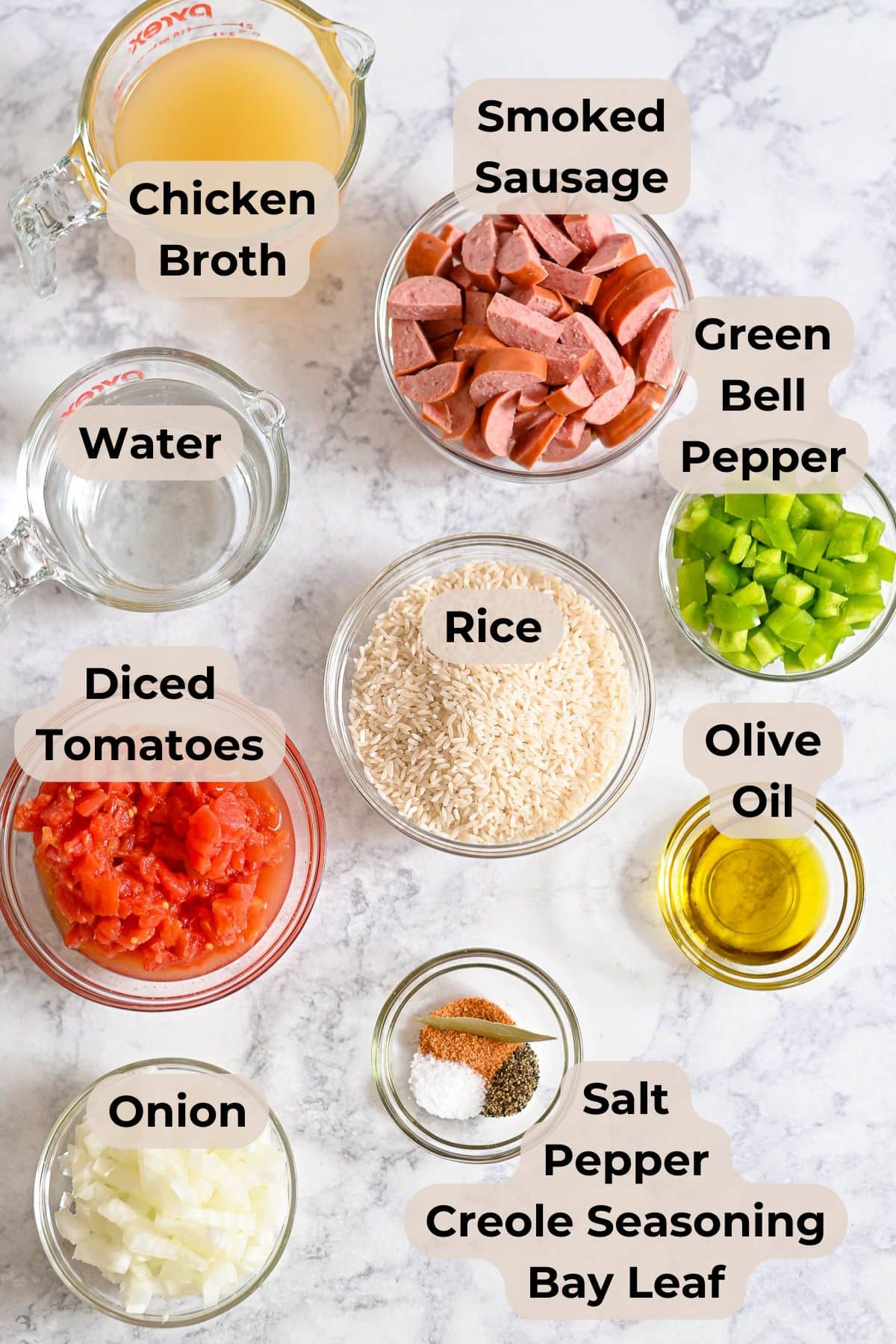 Labeled ingredients for Smoked Sausage Jambalaya, including Hillshire Farm smoked sausage, chicken broth, rice, veggies, seasonings, and olive oil-everything you need for the best smoked sausage for jambalaya.