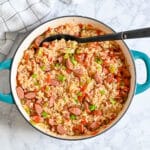 A pot of sausage jambalaya with rice, vegetables, and the best smoked sausage for jambalaya, topped with chopped green onions.