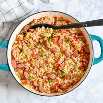 A pot of sausage jambalaya with rice, vegetables, and the best smoked sausage for jambalaya, topped with chopped green onions.