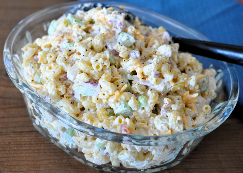 Rotisserie Chicken Macaroni Salad in a clear bowl with a black spoon.