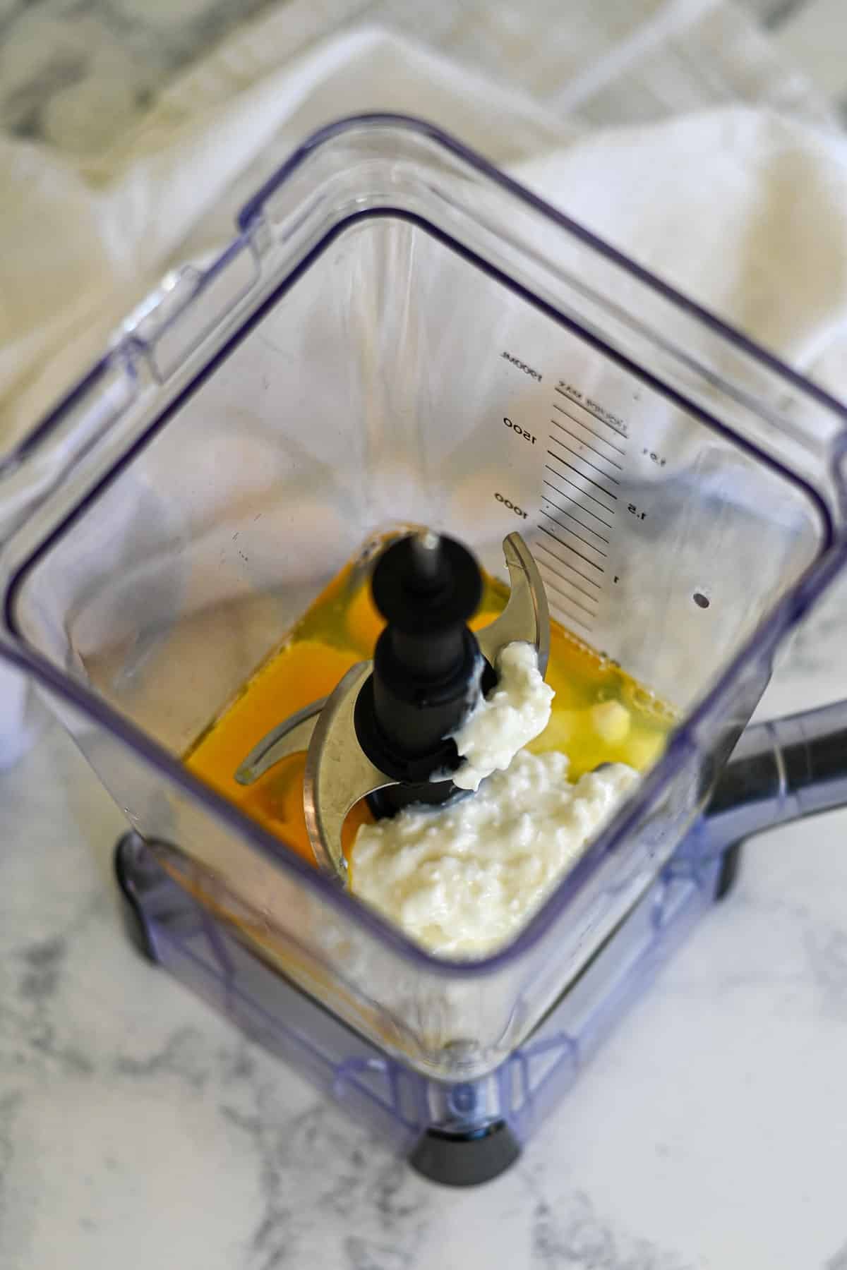 Overhead view of a blender with eggs and cottage cheese inside, ready to be mixed for delicious Spinach Egg Cups.