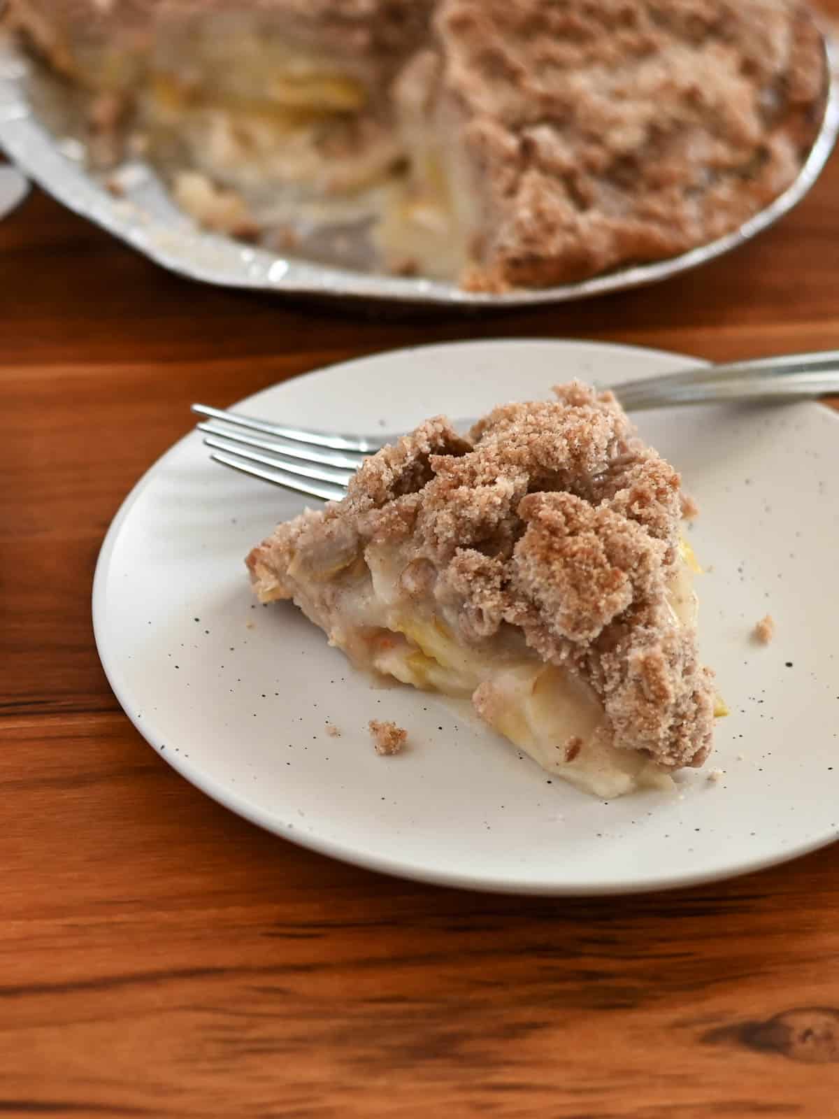 A slice of pie made with fresh pears on a plate with a fork. 