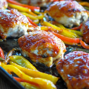 baked chicken thighs with peppers on a cookie sheet