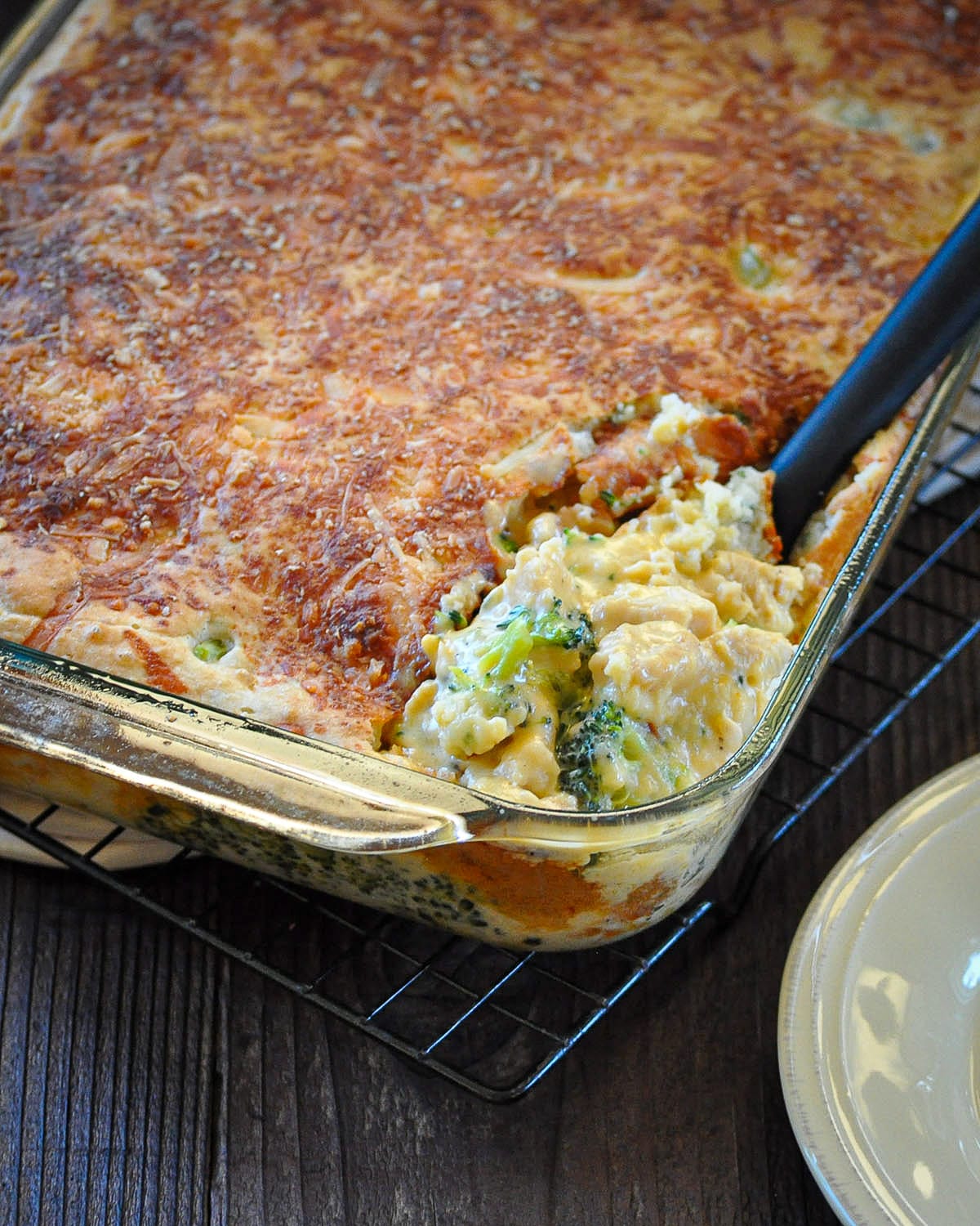 just baked chicken divan being scooped out of a casserole dish with a big black spoon. 