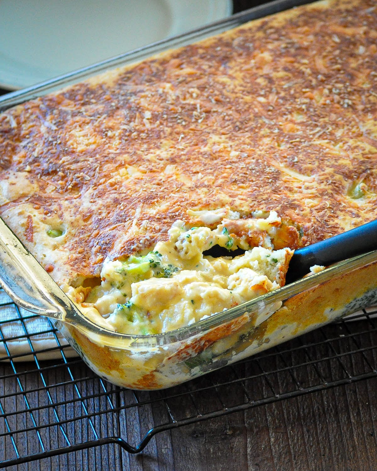 just baked chicken divan being scooped out of a casserole dish with a big black spoon.