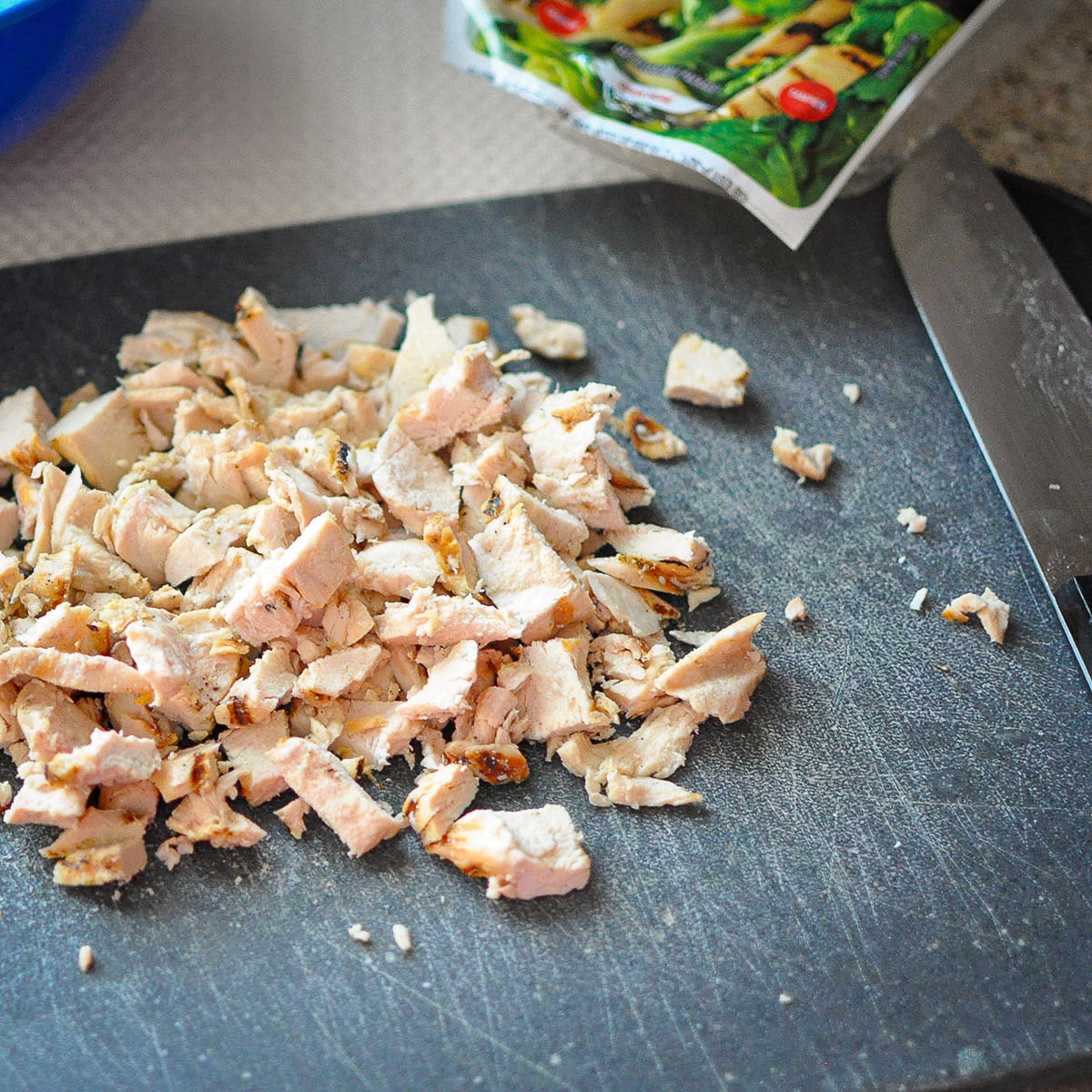 cubed cooked chicken on a black cutting board.