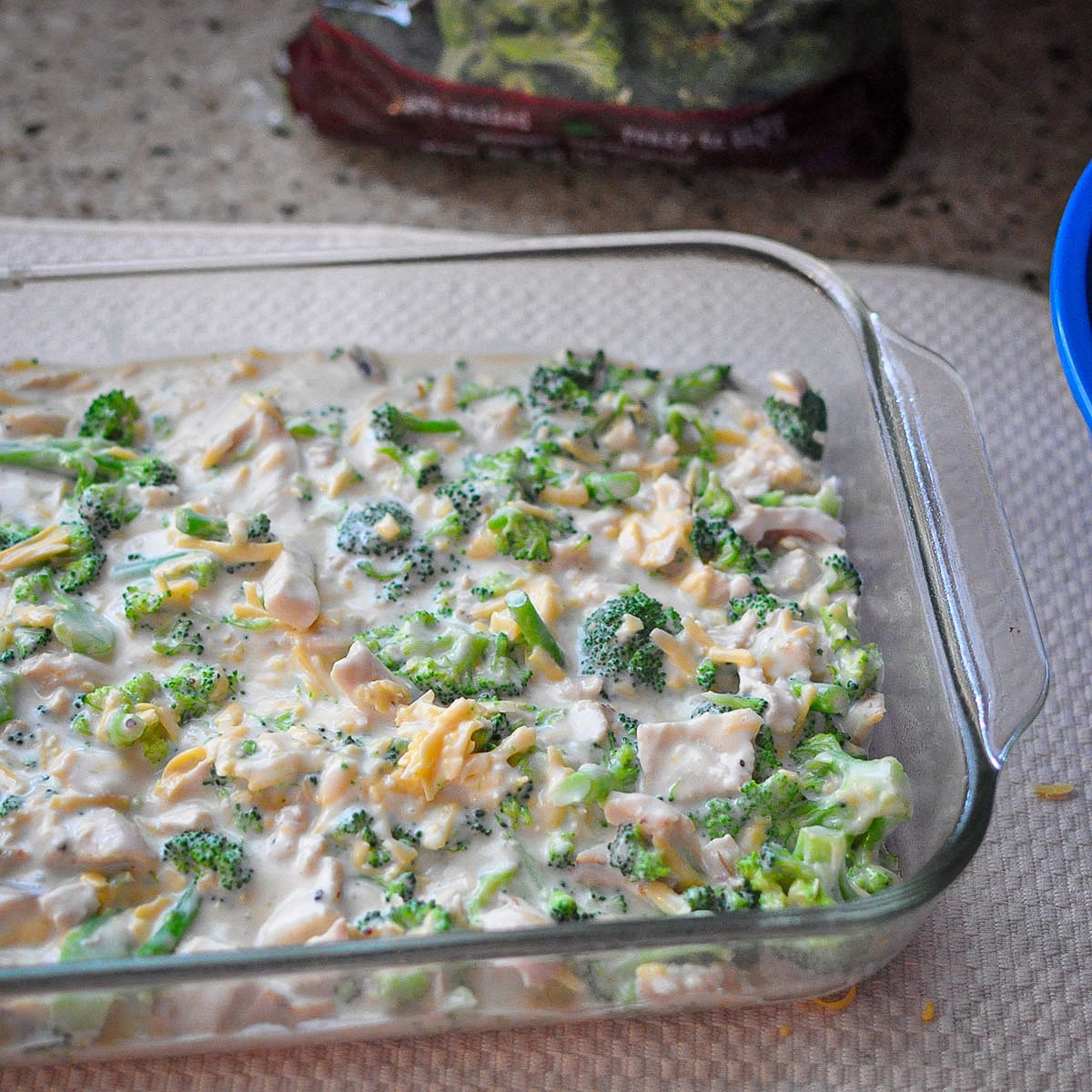 a casserole dish with chicken, cheese, broccoli and alfredo sauce. 