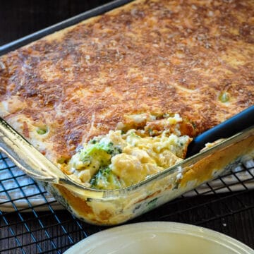 cheesy chicken with broccoli and a biscuit topping in a baking dish being served.