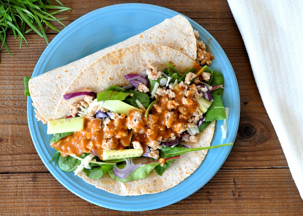 Chicken Sesame Ginger Wraps on a blue plate next to a white napkin. 