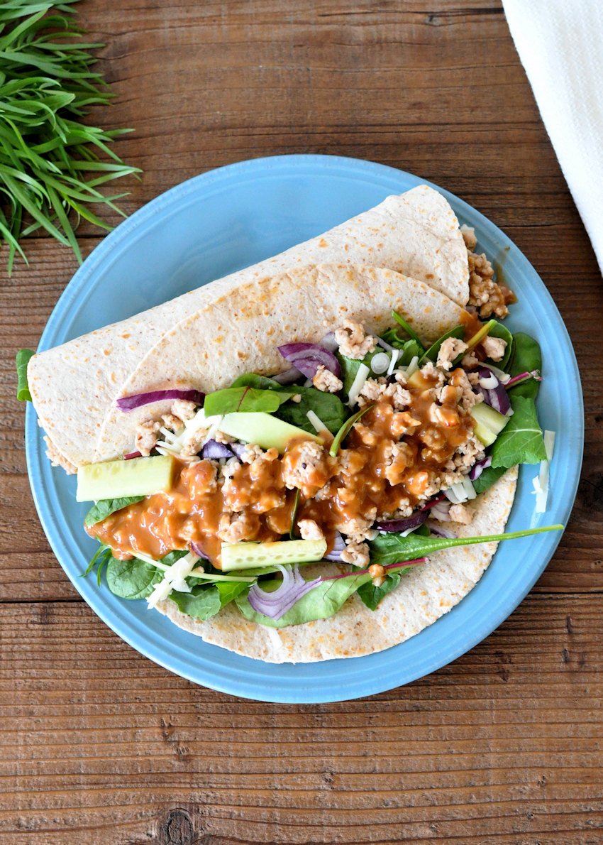 a chicken wrap filled with lettuce on a blue plate