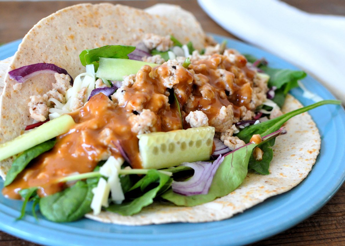 ground chicken with sesame ginger sauce in a tortilla on a blue plate