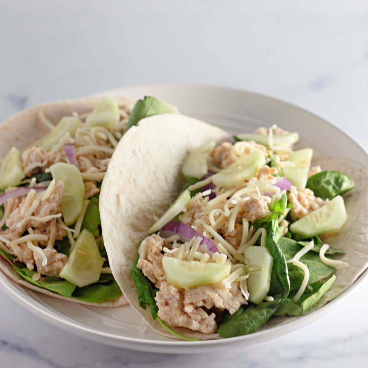Two sesame wraps filled with ground chicken, spinach, cucumber.