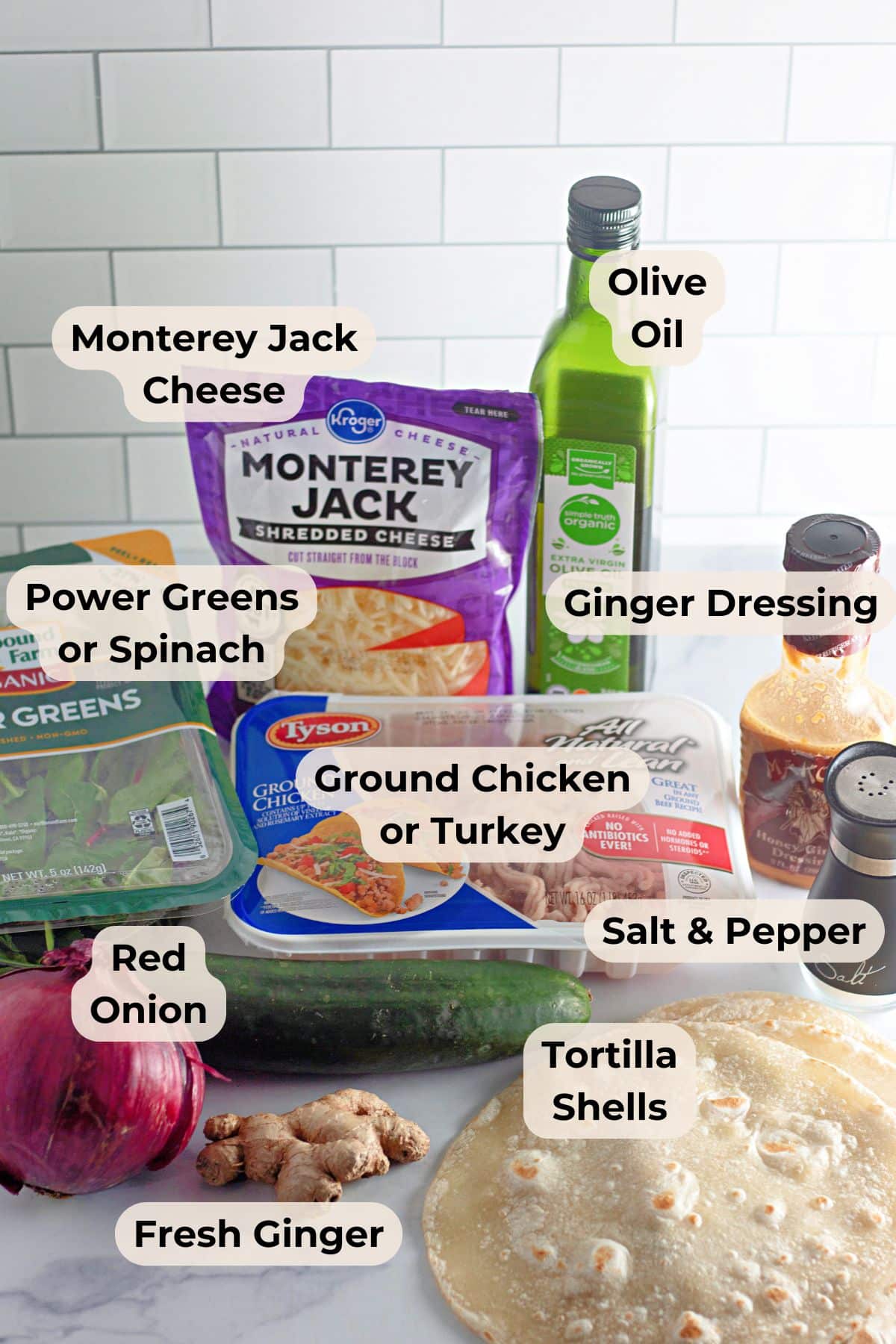 Various labeled ingredients on a kitchen counter, including cheese, greens, oil, meat, onion, ginger, and tortillas-perfect for preparing delicious Chicken Sesame Ginger Wraps.
