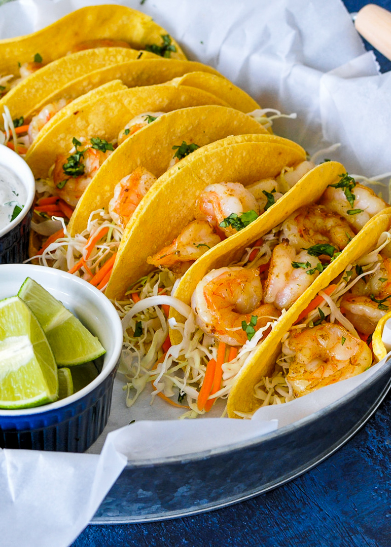 a close up of shrimp tacos with cabbage, carrots and cilantro