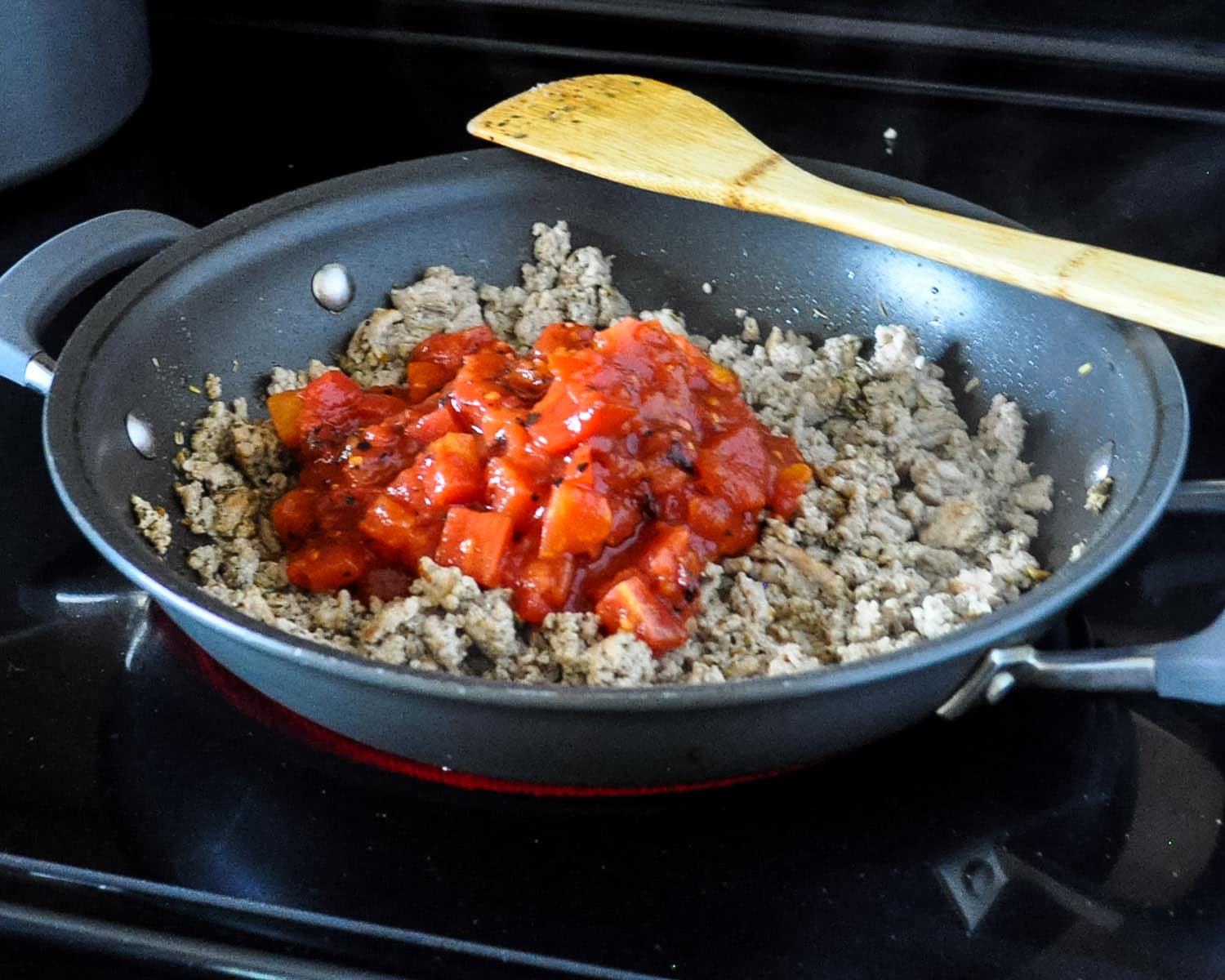 ground turkey and spices with tomatoes cooking in a skillet