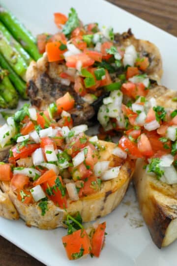 pico de gallo over grilled swordfish steaks next to asparagus