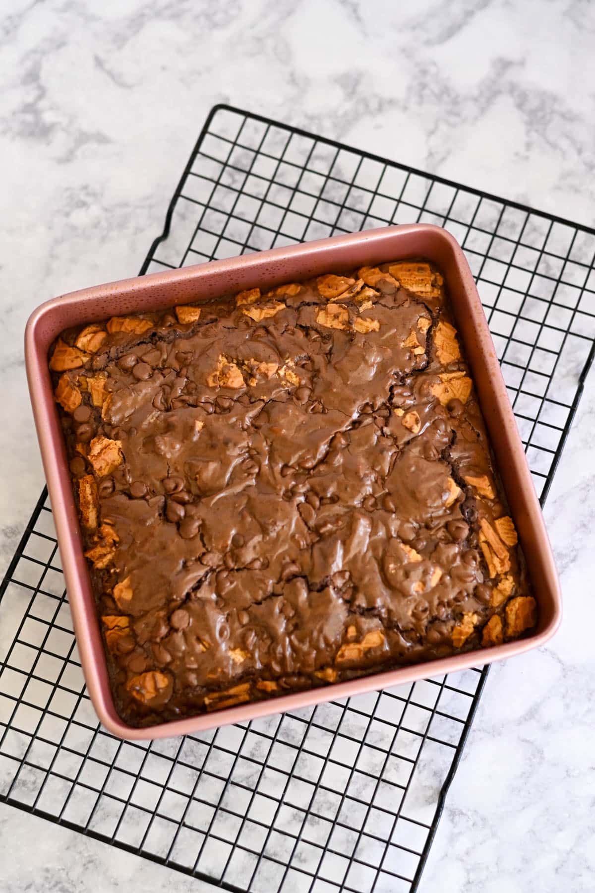 Nutter Butter Chocolate Chip Brownies with a crumbly top rest in a square pan on a cooling rack.