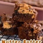 Close-up of stacked Nutter Butter Chocolate Chip Brownies on a cooling rack, with more nutter butter brownies in the background.