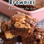 Three Nutter Butter Chocolate Chip Brownies stacked on a cooling rack, with a pan of brownies in the background.