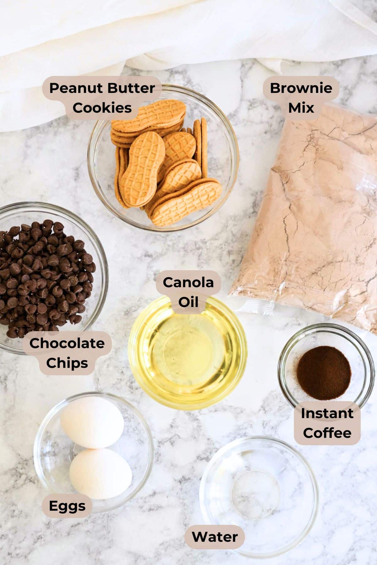 Labeled ingredients for Nutter Butter Chocolate Chip Brownies: cookies, brownie mix, chocolate chips, oil, eggs, coffee, and water on a counter.