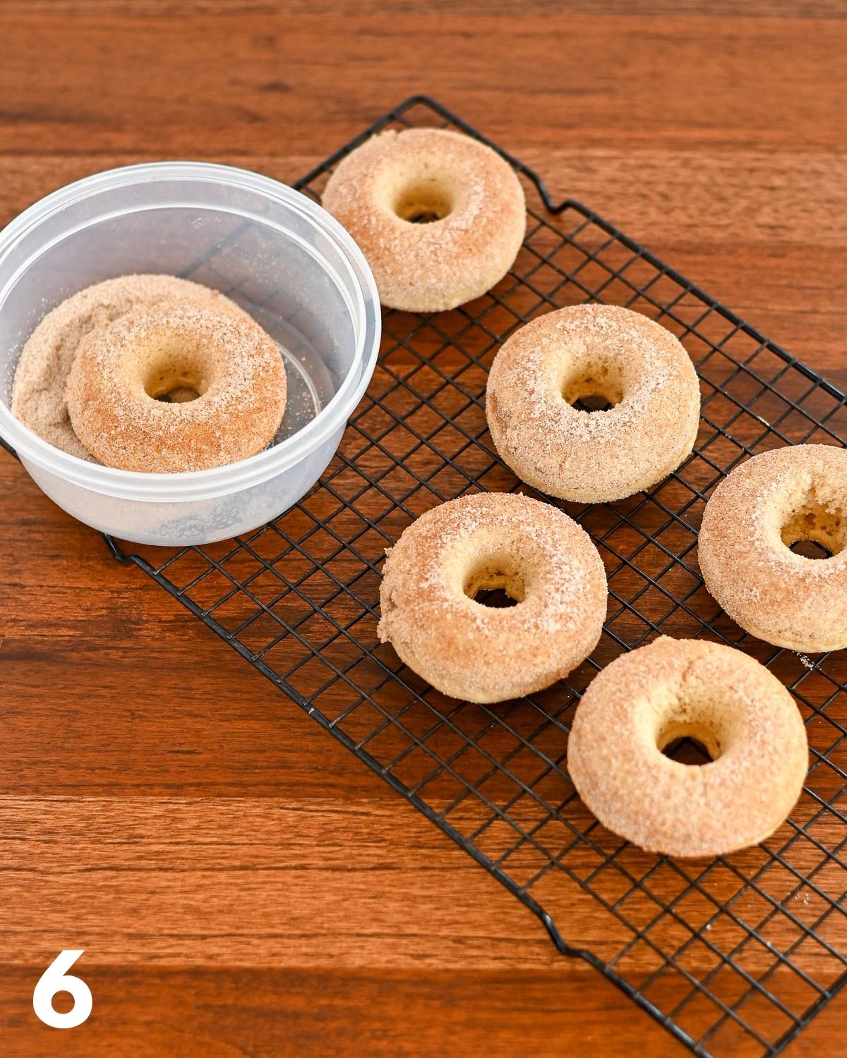 Baked donuts being covers with cinnamon sugar. 