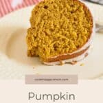 A slice of Pumpkin Bundt Cake with orange glaze sits on a cream plate, topped with light icing.