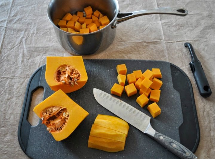 a butternut squash that has been peeled and is in the process of being cubed. 