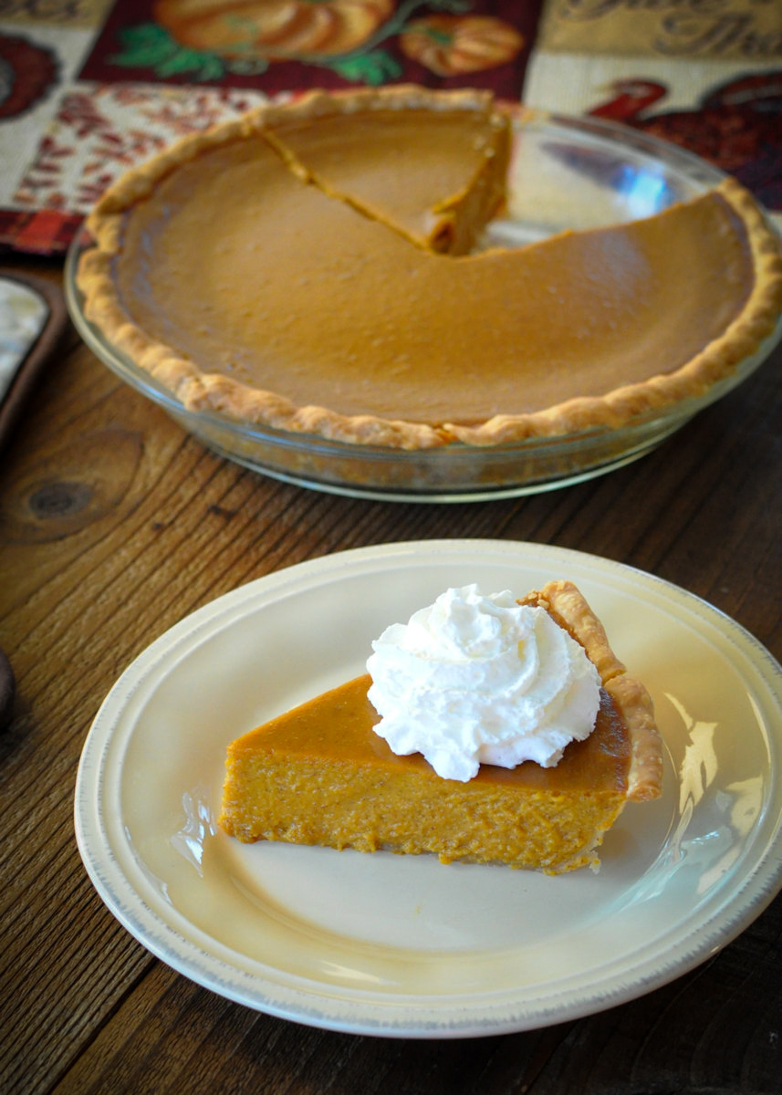 a slice of butternut squash pie with whipped cream on a cream colored plate
