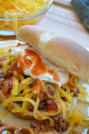 taco meat with salsa, cheese, and sour cream on a bun