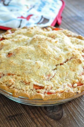 a pie sitting on a brown background next to a red hot pad