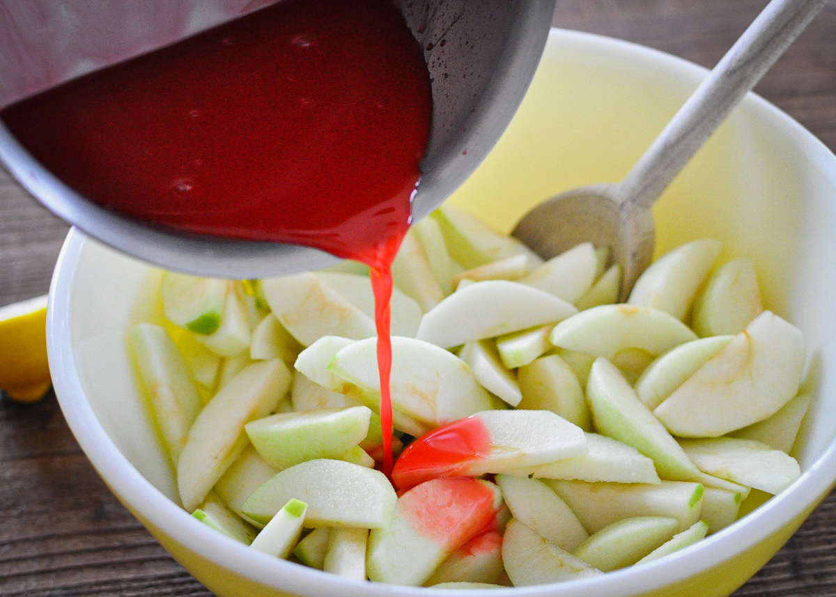 red hot candy sauce being poured over sliced granny smith apples